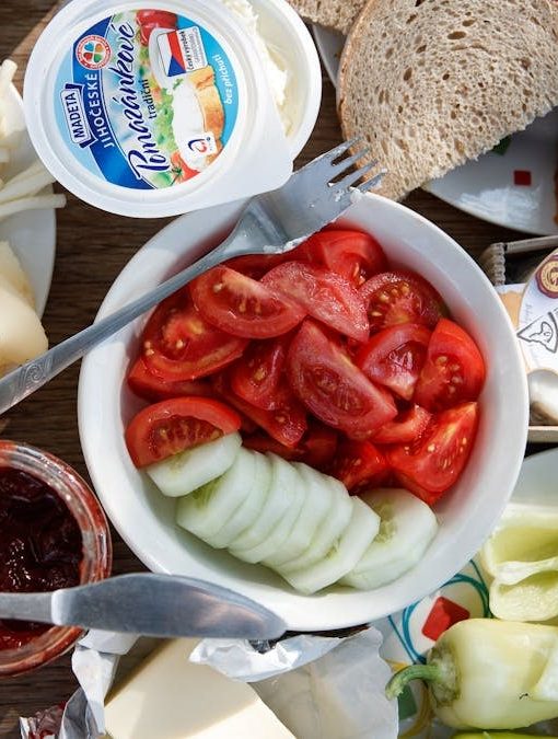 Delicious breakfast setup with cheese, cold cuts, bread, and fresh vegetables.