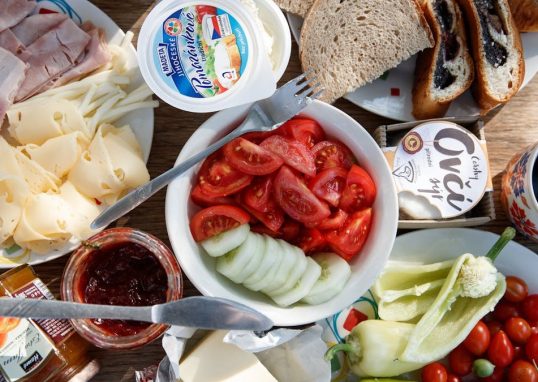 Delicious breakfast setup with cheese, cold cuts, bread, and fresh vegetables.