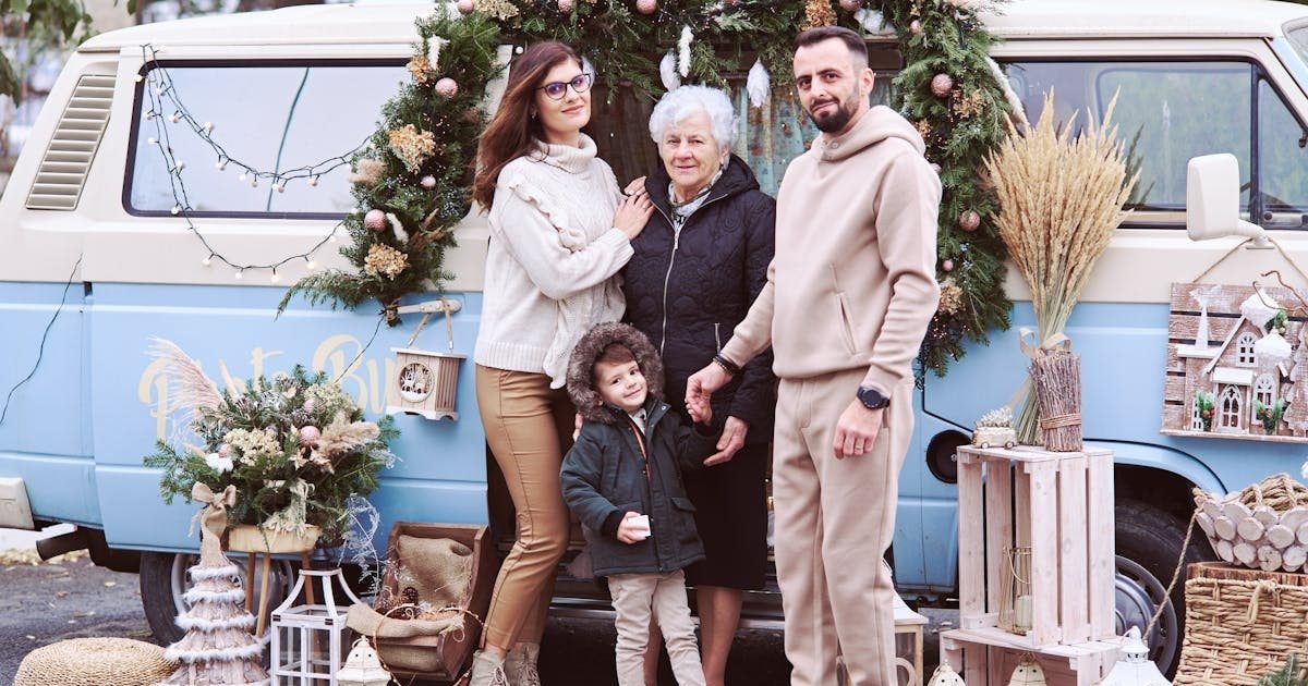 A multi-generational family posing with festive Christmas decorations outside a decorated van.