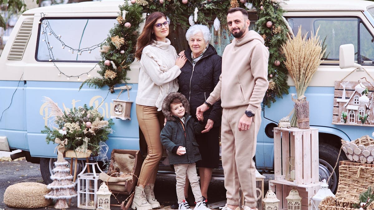 A multi-generational family posing with festive Christmas decorations outside a decorated van.